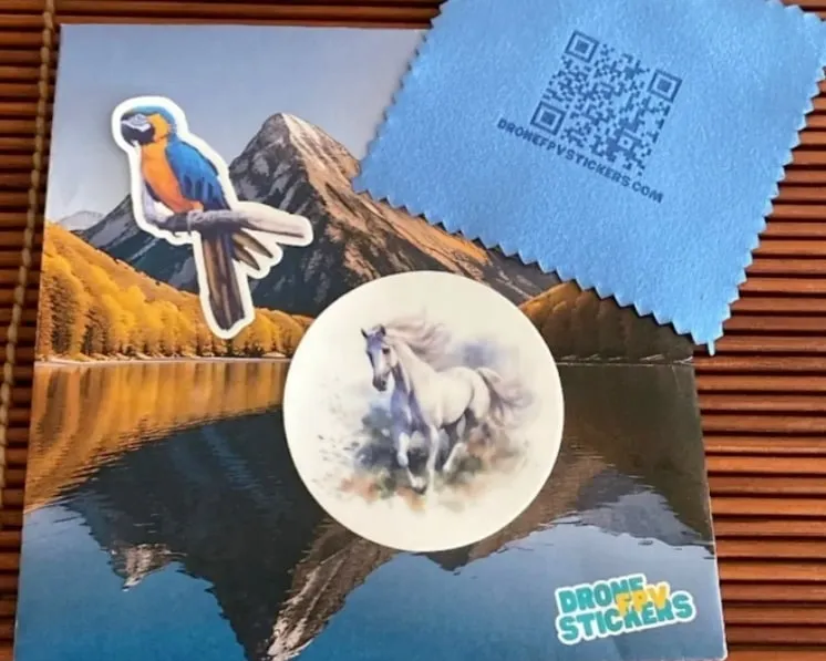 A parrot sticker and a round horse sticker on a Drone FPV Stickers card, next to the QR cleaning cloth