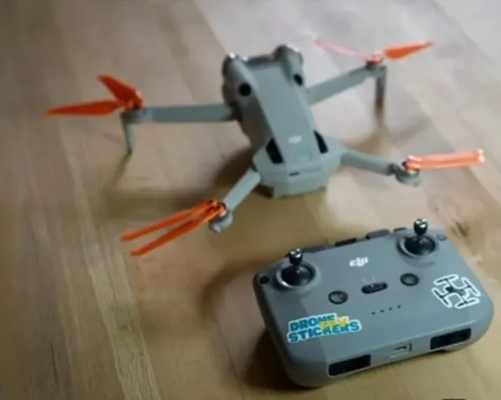 A DJI drone and its remote, with a Drone FPV Stickers logo sticker and a drone sticker on the remote